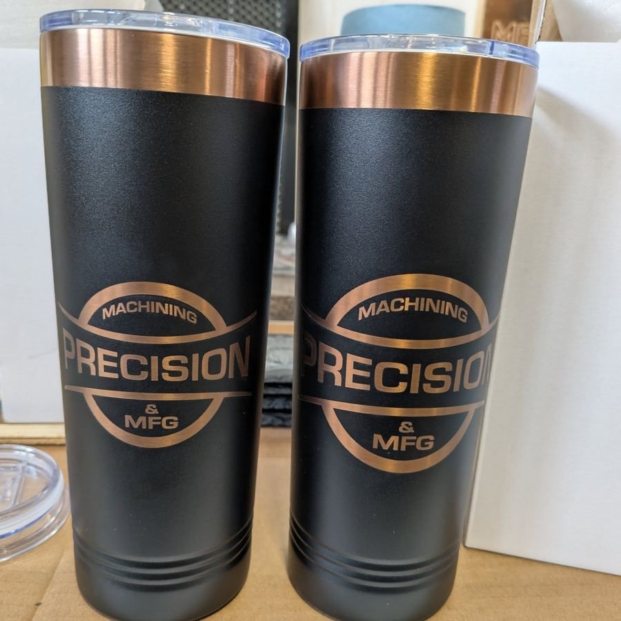 Two black insulated tumblers with a copper-coloured engraved company logo